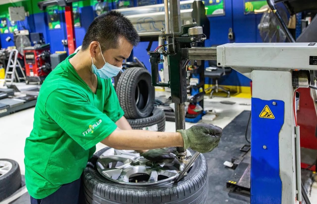 Technician fitting tyre onto wheel using heavy-duty tyre mounting machinery